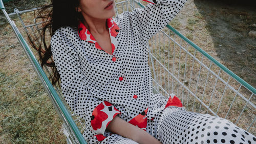 Midsection of woman sitting on shopping cart outdoors