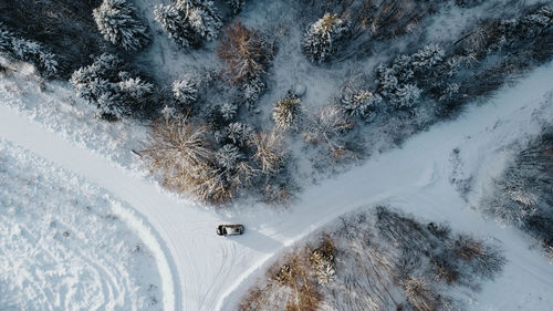 Aerial view of forest nountaiin winter with snowy trees. three to four roads with car in the middle.