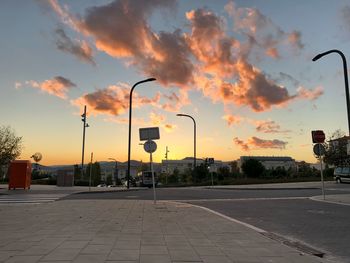 Street lights by road against sky during sunset