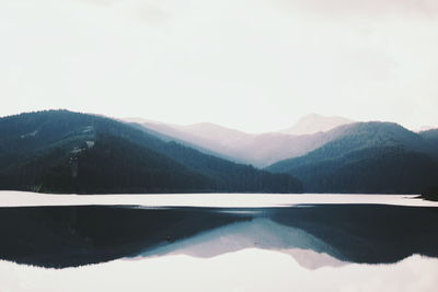 Scenic view of lake and mountains against clear sky