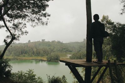 Man standing by lake against sky