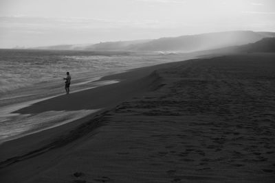 Man walking on beach against sky
