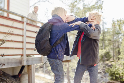 Brothers fighting while mother looking at them from balcony