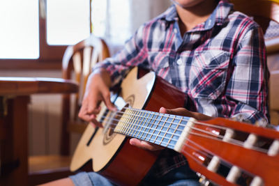 Midsection of man playing guitar