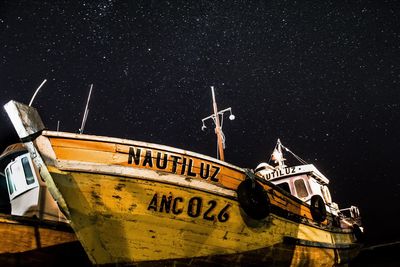 Boats moored in sea against star field