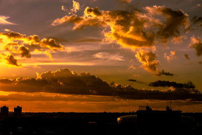 Silhouette buildings against dramatic sky during sunset