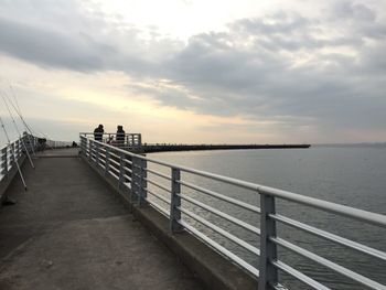 Pier over sea against sky during sunset