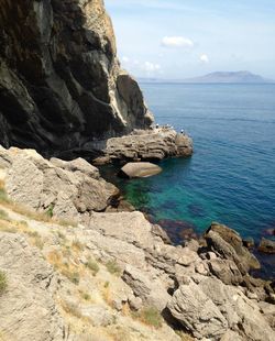 Scenic view of rocks by sea against sky