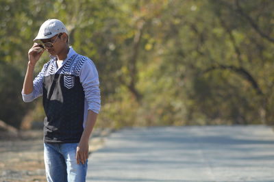 Young man wearing sunglasses while standing on road