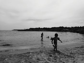Children on beach against sky