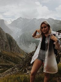 Portrait of young woman standing on mountain against sky