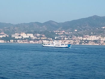 Scenic view of sea by townscape against clear sky