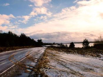 Road amidst field against sky during winter