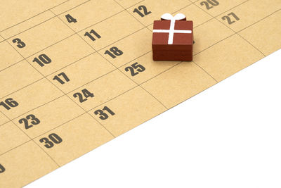 Close-up of wooden block on calendar over white background