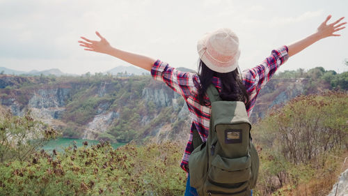 Midsection of woman with arms raised against mountain range