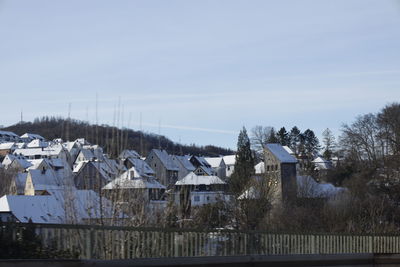 Houses by buildings against sky during winter