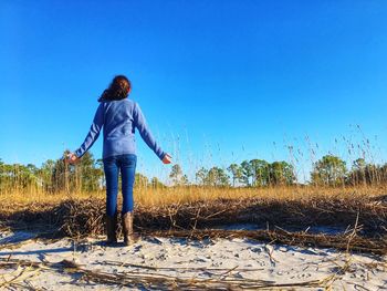 Rear view of woman standing on field against clear sky