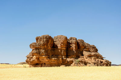 Rock formations on landscape against clear blue sky