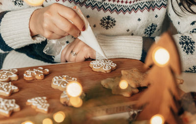 Close-up photo of woman decorating gingerbread christmas cookies at home