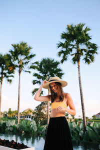 Woman standing by tree against sky