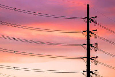 Low angle view of electricity pylon against pink sky during sunset