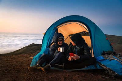 Brothers talking while camping on mountain during sunset