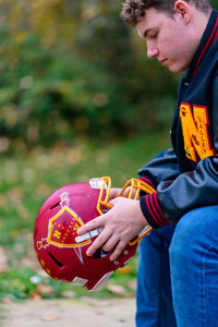 Young man holding football helmet