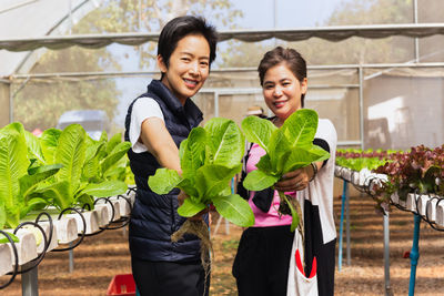 Portrait of smiling friends standing in greenhouse