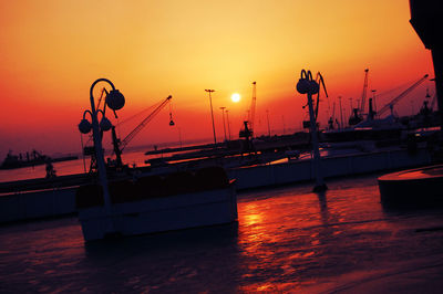 Silhouette boats in sea against orange sky