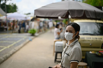 Young women wear surgical protection mask and standing in front of food truck in street market