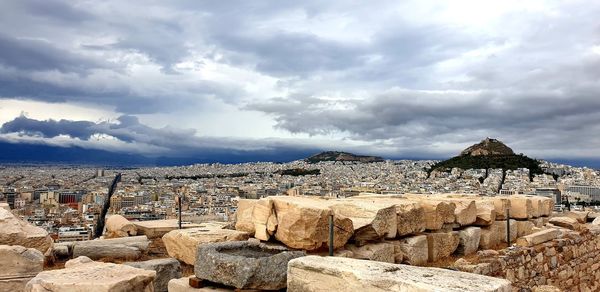 View of rocks in city against cloudy sky