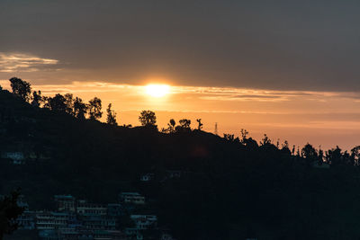 Silhouette trees on landscape against sky during sunset