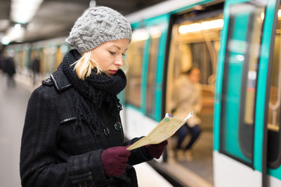 Full length of young woman in train at railroad station during winter