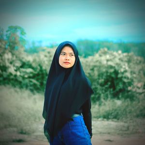 Portrait of beautiful young woman standing on land