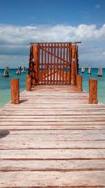Wooden pier amidst lake against sky on sunny day