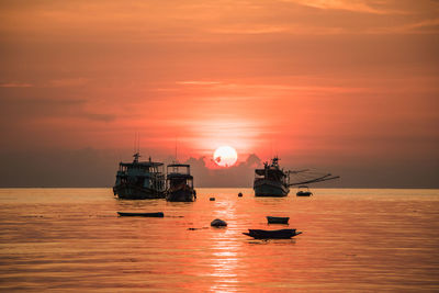 Fishing boat in sea against sky during sunset