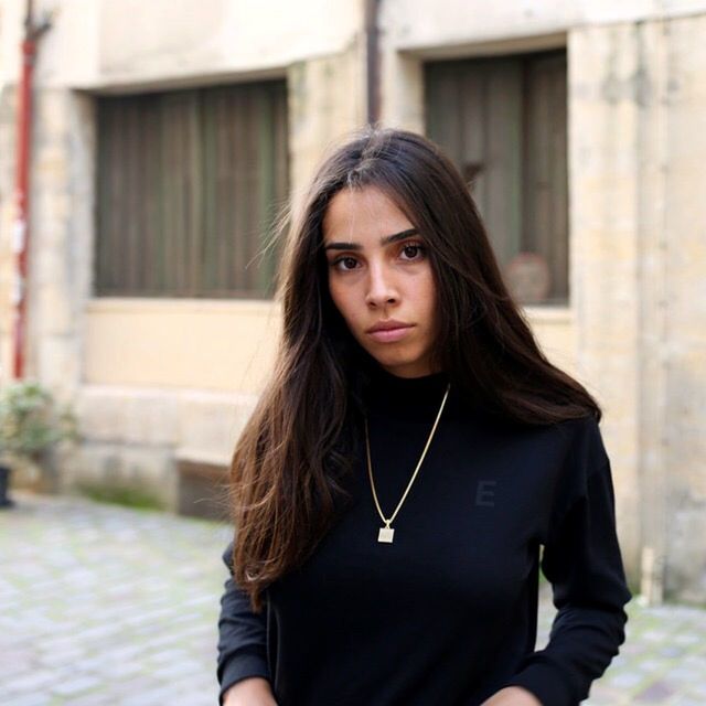 portrait, looking at camera, one person, front view, young adult, architecture, hair, long hair, standing, building exterior, beauty, built structure, young women, focus on foreground, day, waist up, beautiful woman, black hair, hairstyle, outdoors, teenager