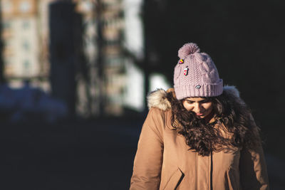 Portrait of young woman standing by tree during winter