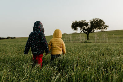 Brother and sister walking on grass field