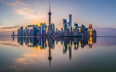 Modern city with high-rise buildings against the backdrop of sunset and reflection in the water