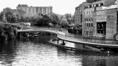 Bridge over river by buildings in city