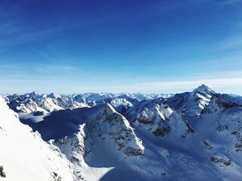 Scenic view of snowcapped mountains against blue sky