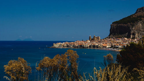 Scenic view of sea by city against clear blue sky