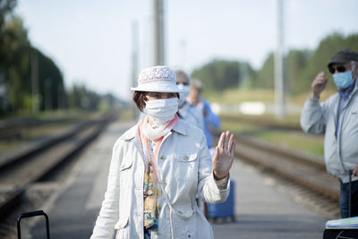 Positive elderly seniors people with face masks waiting train before traveling during a pandemic