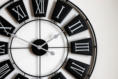 Close-up of black and white classic wall clock with roman numbers