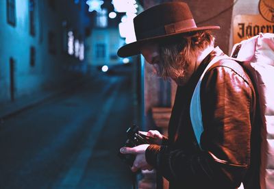 Midsection of man using mobile phone in city at night