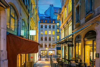 Illuminated street amidst buildings in city