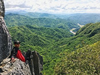 Man sitting on landscape against mountains