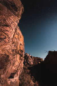 Low angle view of man in  rocky mountains against sky at night