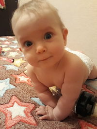 Portrait of cute baby girl lying on bed at home